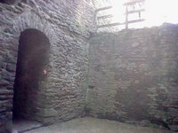 A dark passageway with a halo of light behind a fence the level above